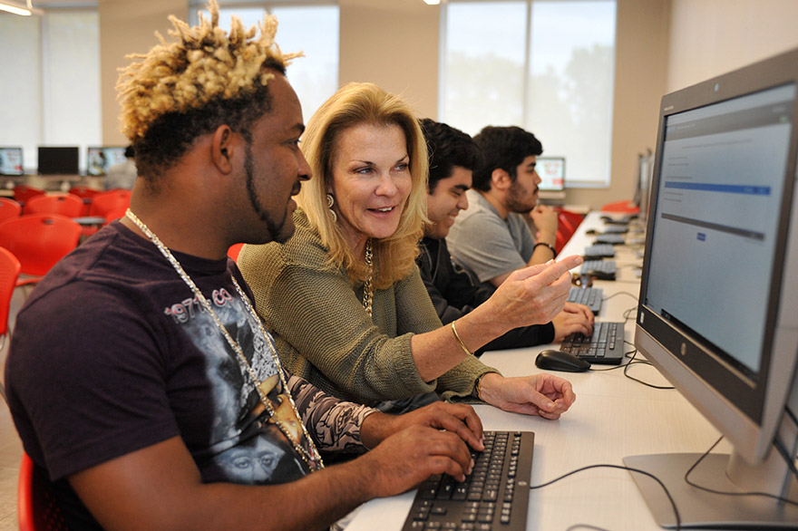 student in front of computer being assisted by union employee