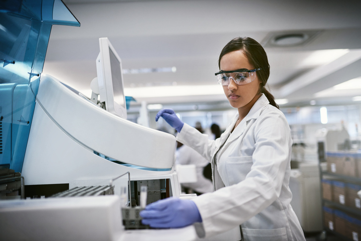 Shot of a young woman using a machine to conduct a medical test in a laboratory