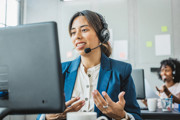 woman in front of computer with headset