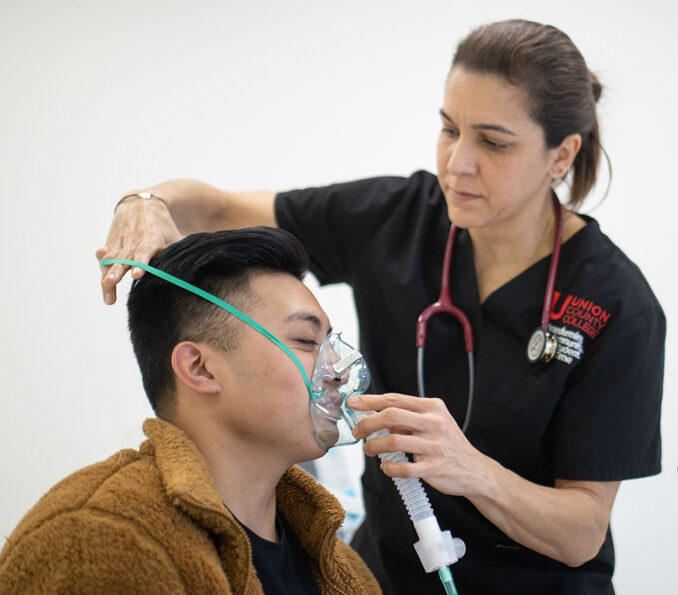 Female nurse putting breathing apparatus over young man's face.